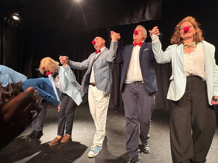 La troupe du Théâtre Sans Nom salue le public sur scène, main dans la main, nez rouges sur le visage.